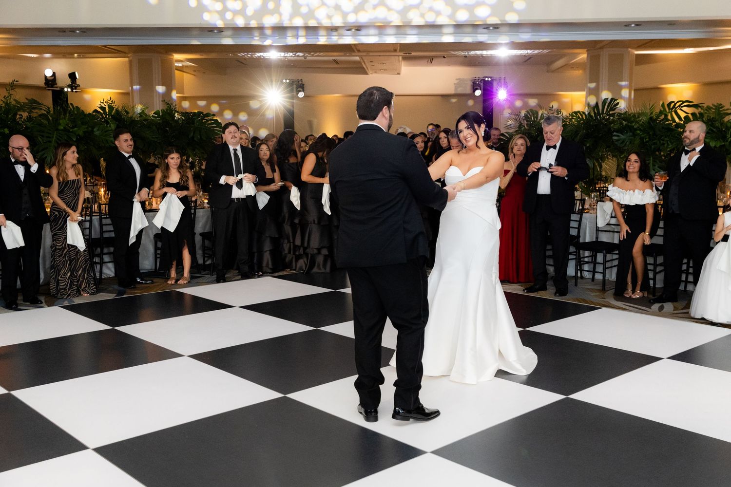 Wedding reception dancing on a classic black and white checkered ballroom floor.