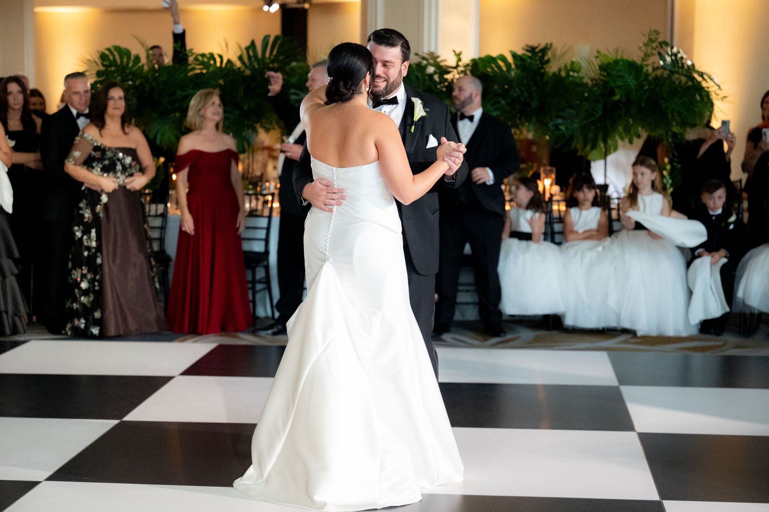 Black and white dance floor creates a dramatic pattern in an upscale event space with floral decor.