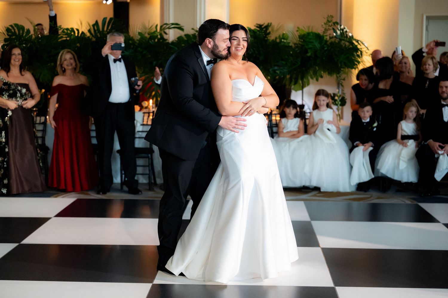 Couples dancing on a black and white checkered dance floor at an elegant wedding reception.