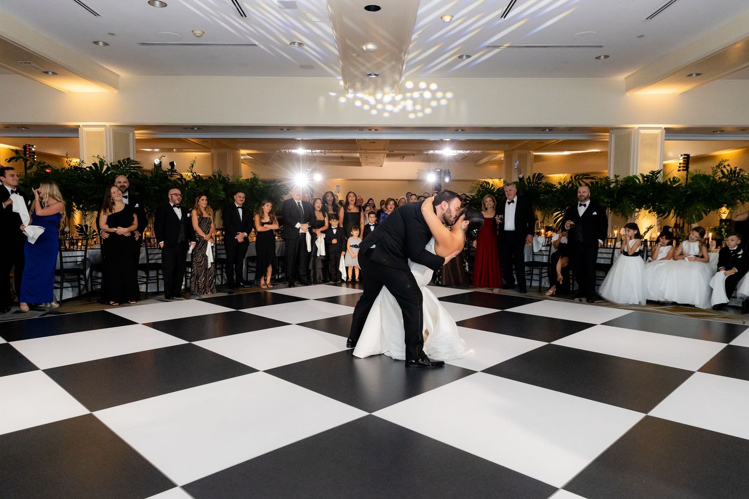 Black and white checkered dance floor at an elegant reception venue with decorative lighting.