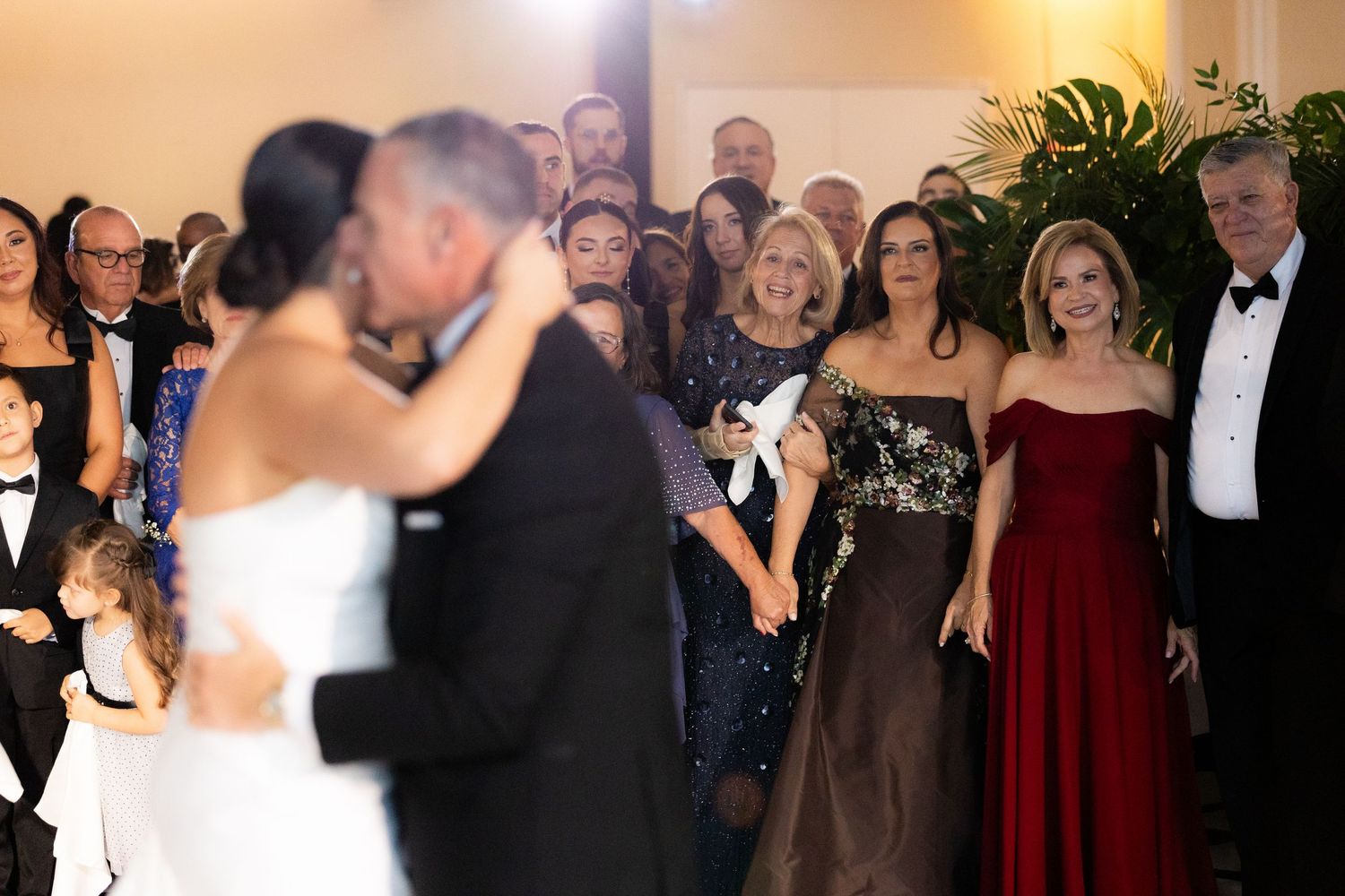 Formal evening celebration with guests in elegant attire surrounding a dance floor.