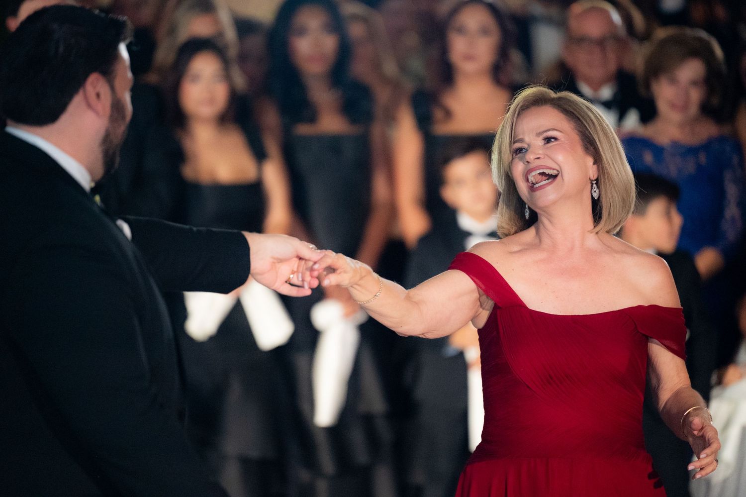 Woman in red dress dances joyfully at formal event.