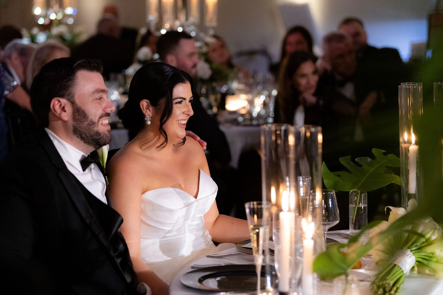 A romantic candlelit dinner reception features elegant tablescapes with glowing tapered candles and greenery.