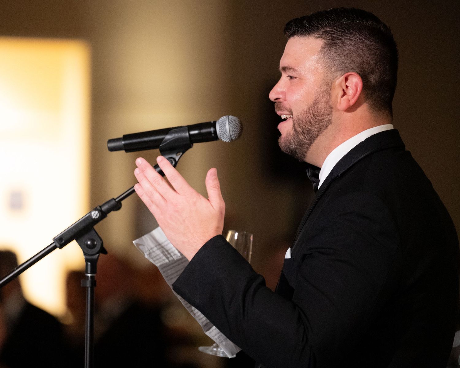 Close-up shots of a performer singing into a microphone at an elegant event in formal attire.