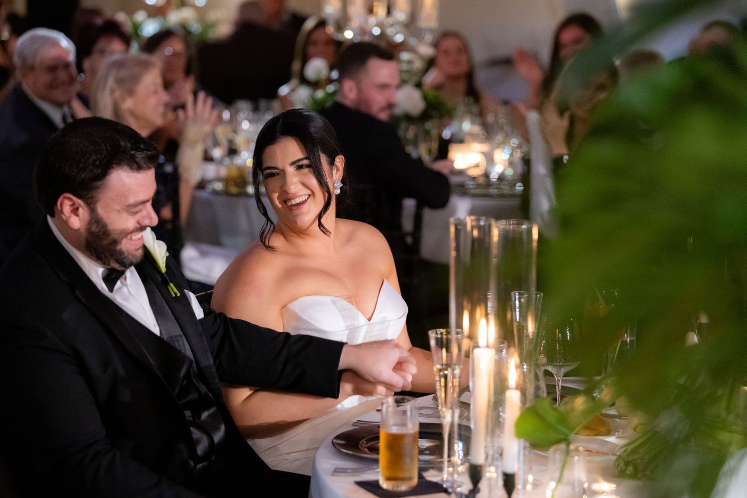 Couple at an elegant candlelit wedding reception sharing an intimate moment together at a dining table.