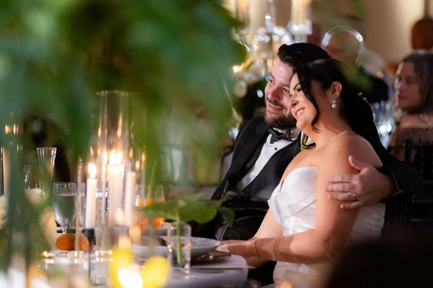 Romantic candlelit wedding reception dinner with tropical foliage decorations.