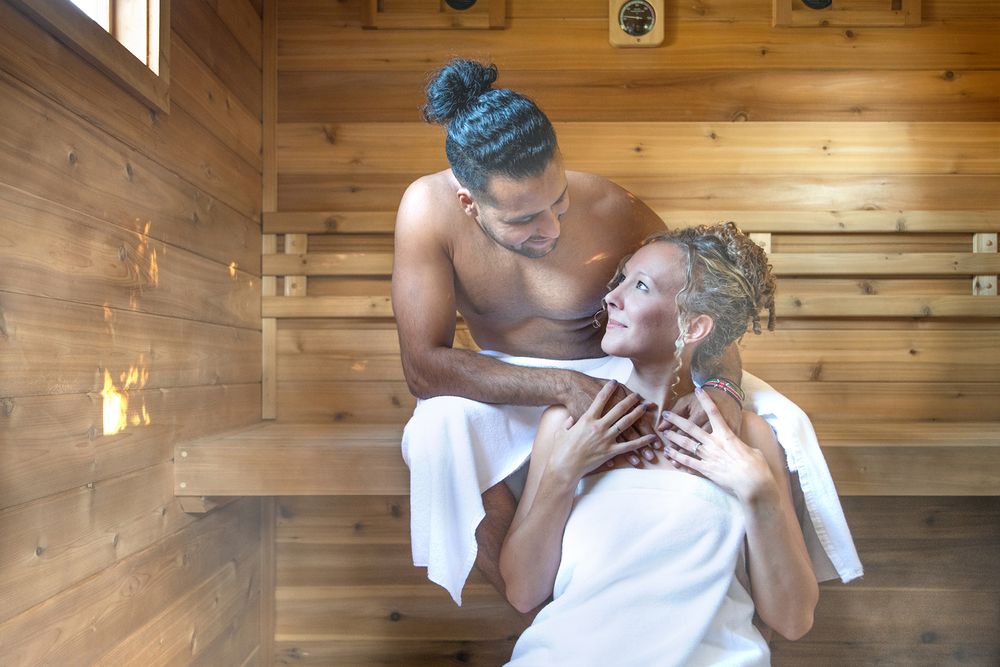 Couple sitting in sauna wrapped in towels, sharing warm intimate moment - Okanagan lifestyle branding photography by Tania Veitch.