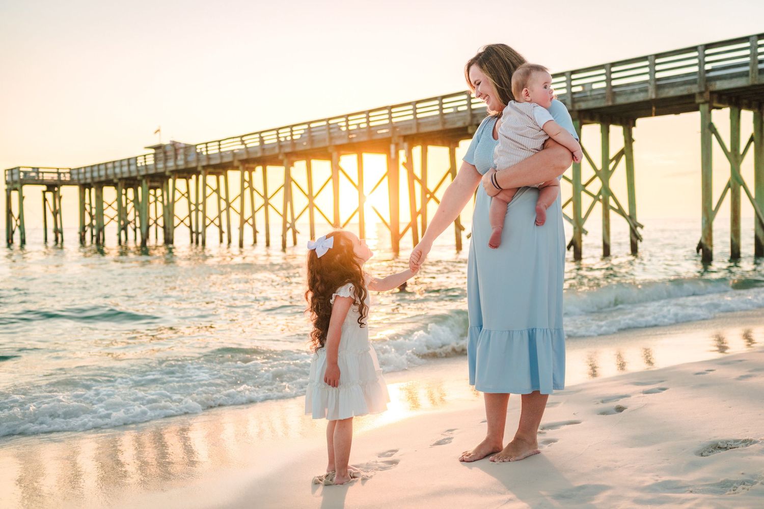 A romantic beach photo session showing people embracing on the sandy shore with turquoise ocean waves in the background.