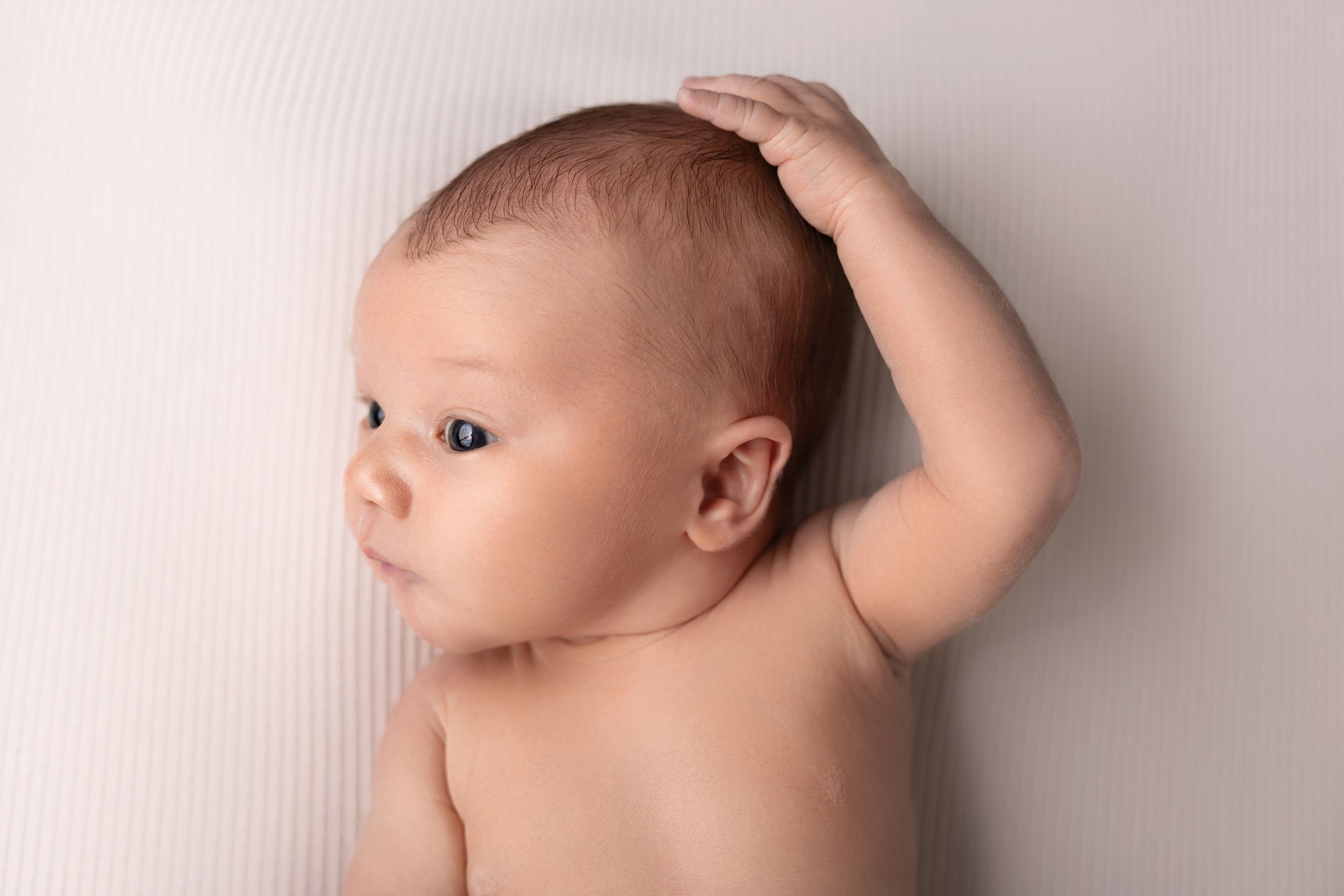 Delicate close-up profile of a sleeping newborn baby against a neutral studio background.