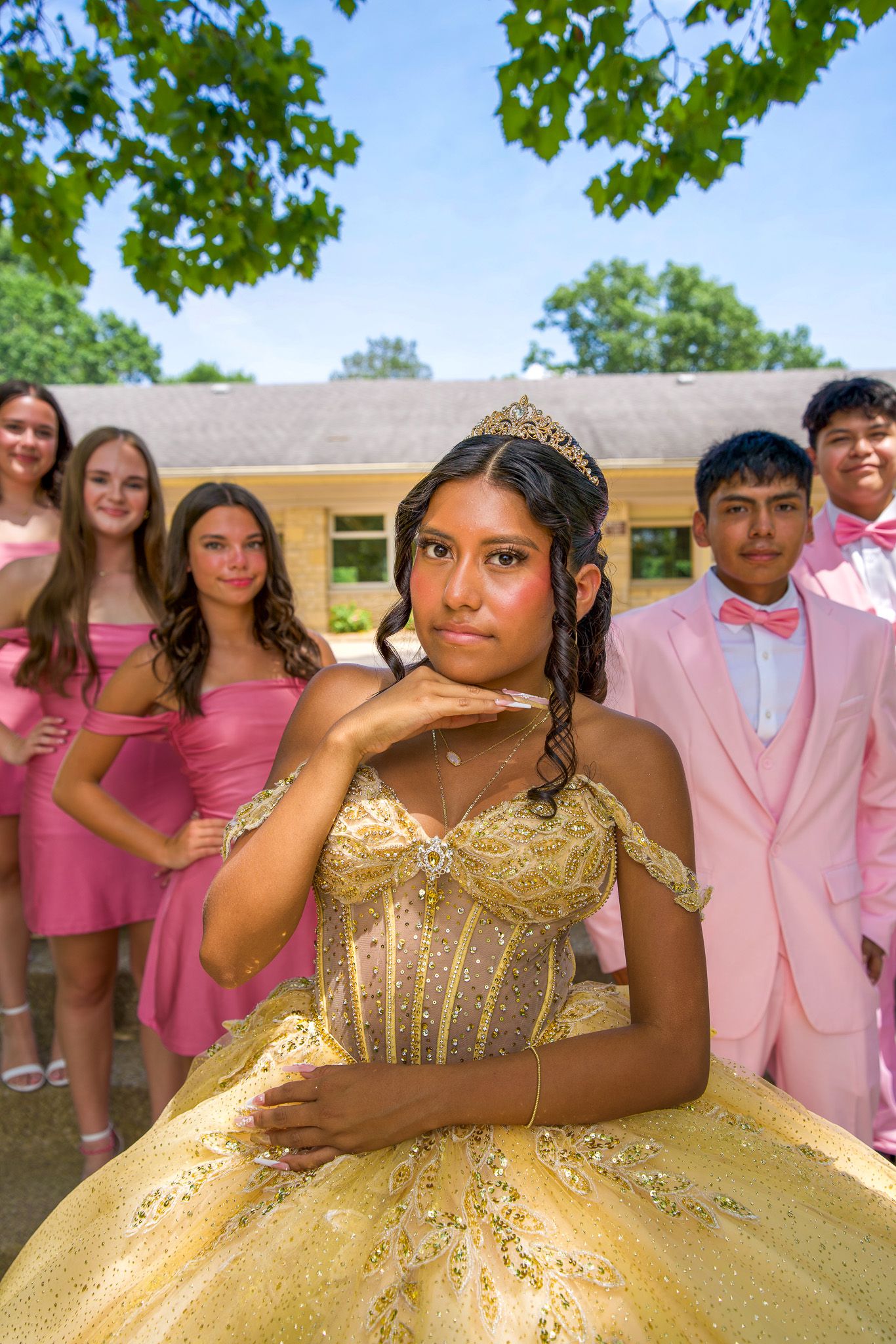QUINCEAÑERA Group photo with people in pink outfits celebrating around someone wearing a gold formal dress.