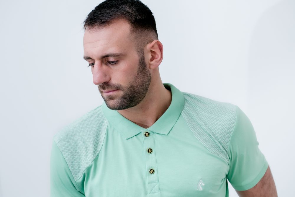 Man wearing a mint green polo shirt with subtle brand logo detail.