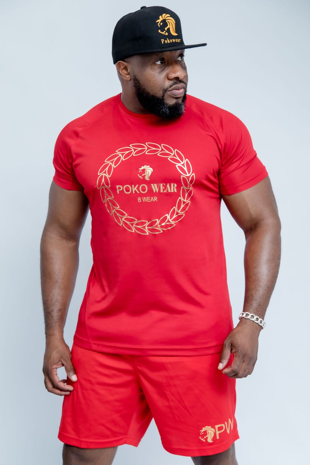 Red athletic wear set with gold circular design motif shown on muscular figure.