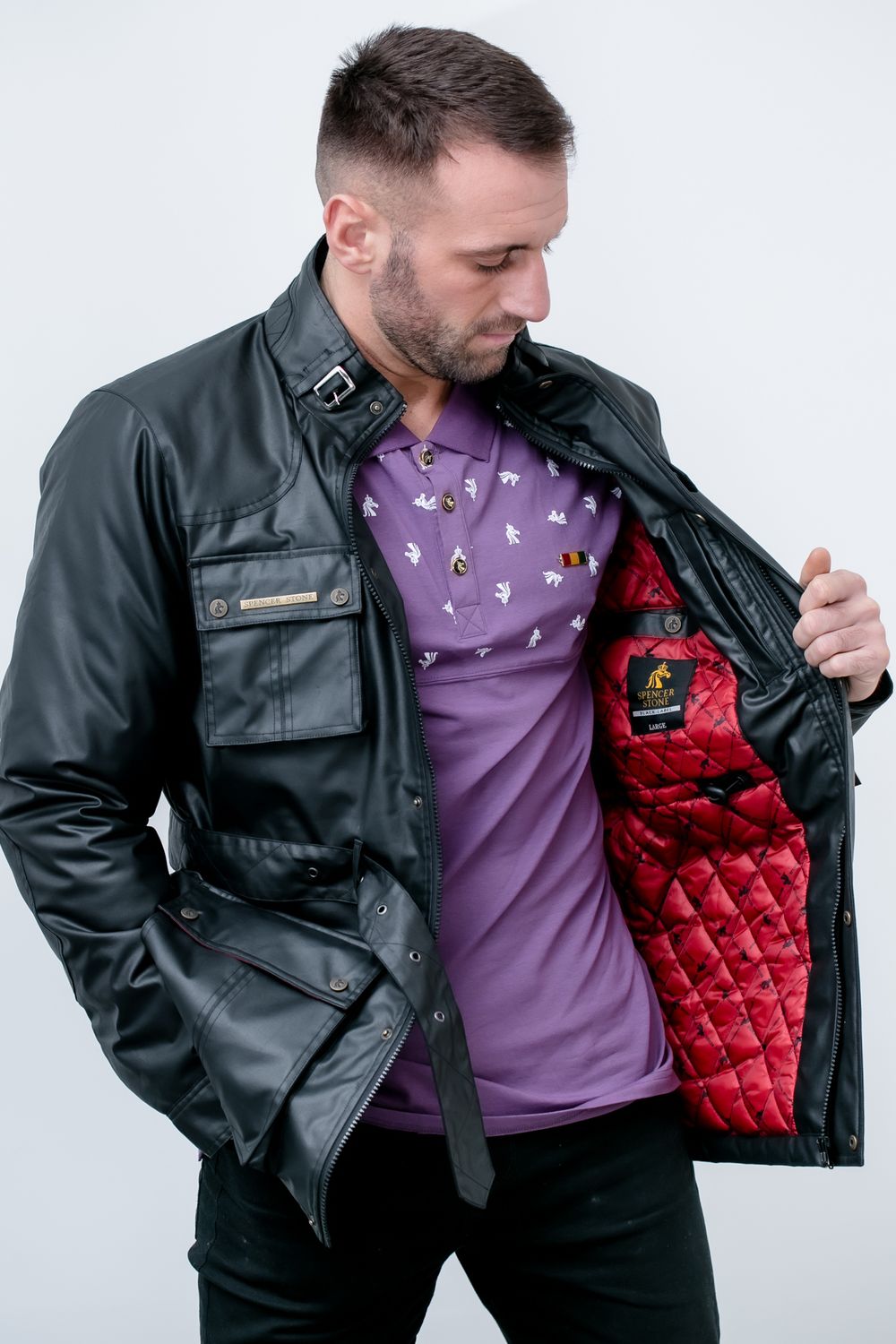 Person wearing black leather jacket with red quilted lining shows details of the garment against white background.