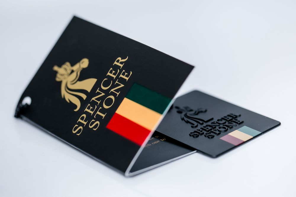 Black luxury business cards with gold foil accents shown at various angles on a light gray surface.