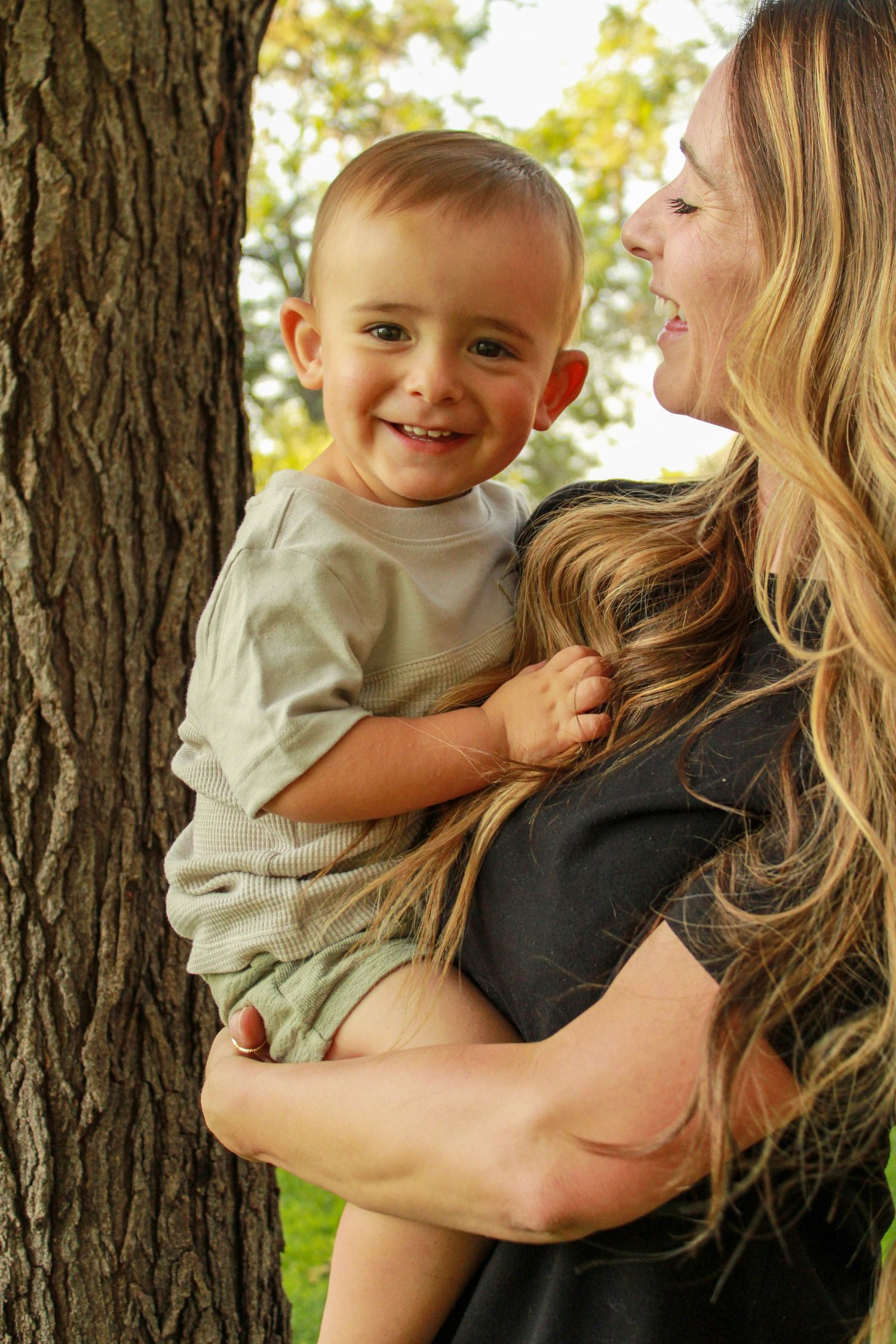A joyful playtime moment outdoors on a sunny afternoon with a light green shirt and natural background.