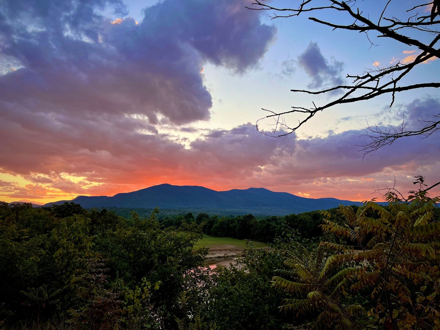 Dramatic sunset panorama of the Moat Mountains with vibrant purple and orange sky in Conway, NH.