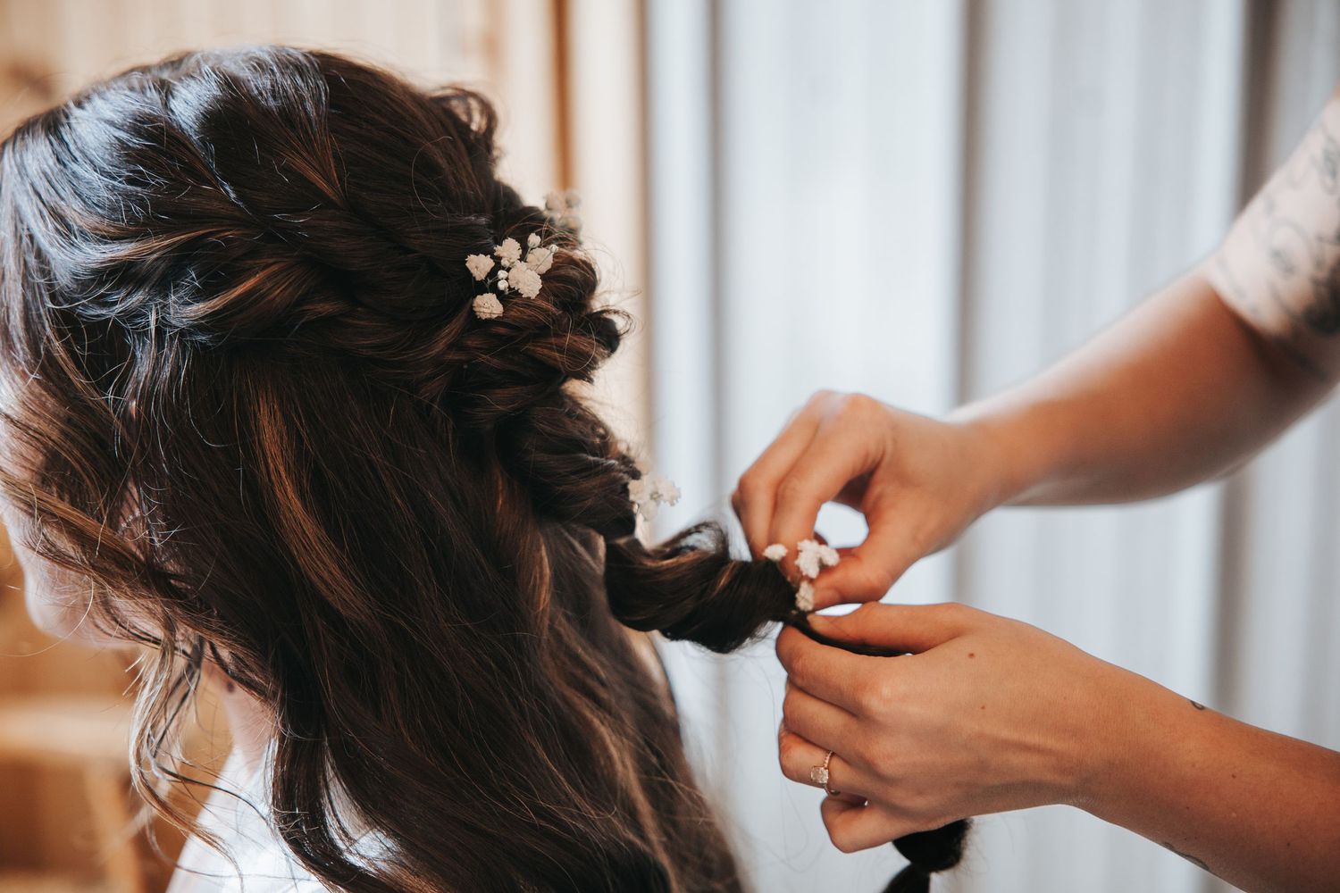 A hairstylist creates a romantic updo hairstyle with loose curls and braids for a special occasion.