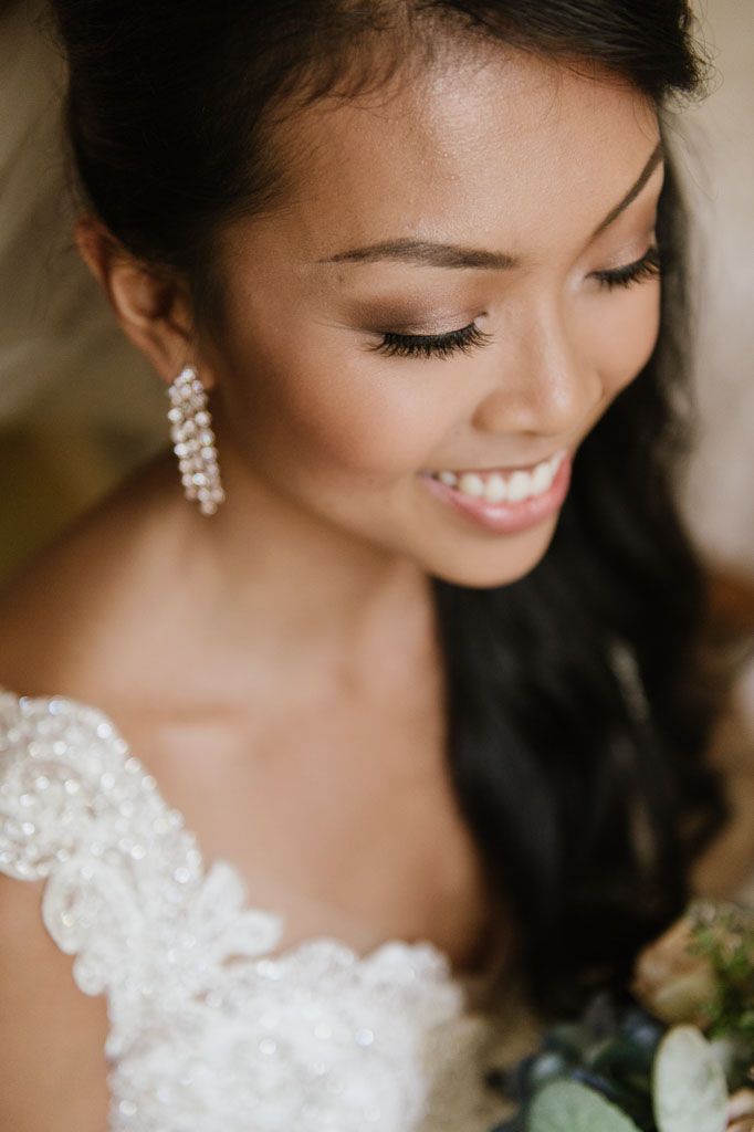 Close up portrait showcasing bridal details including pearls, lace and delicate floral embellishments on white wedding dress.