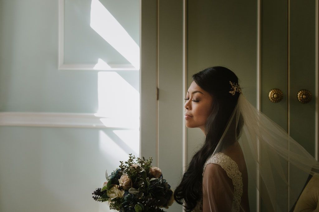 Silhouette of a person relaxing on a window seat gazing thoughtfully into natural daylight streaming in.