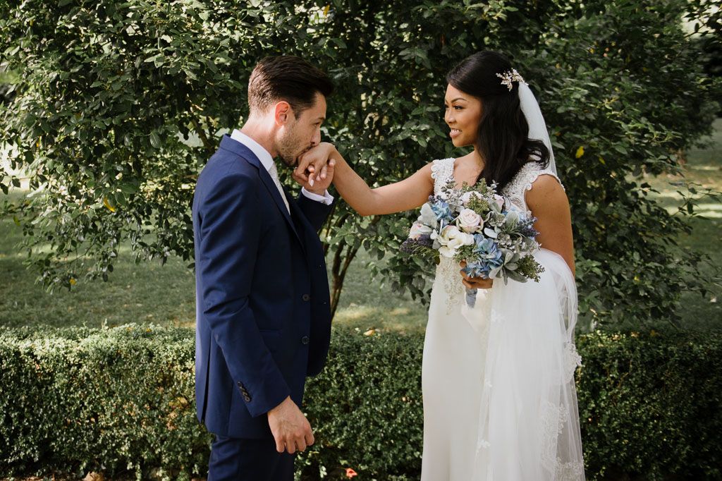 A couple in wedding attire share a romantic dance together in a sunlit garden setting.