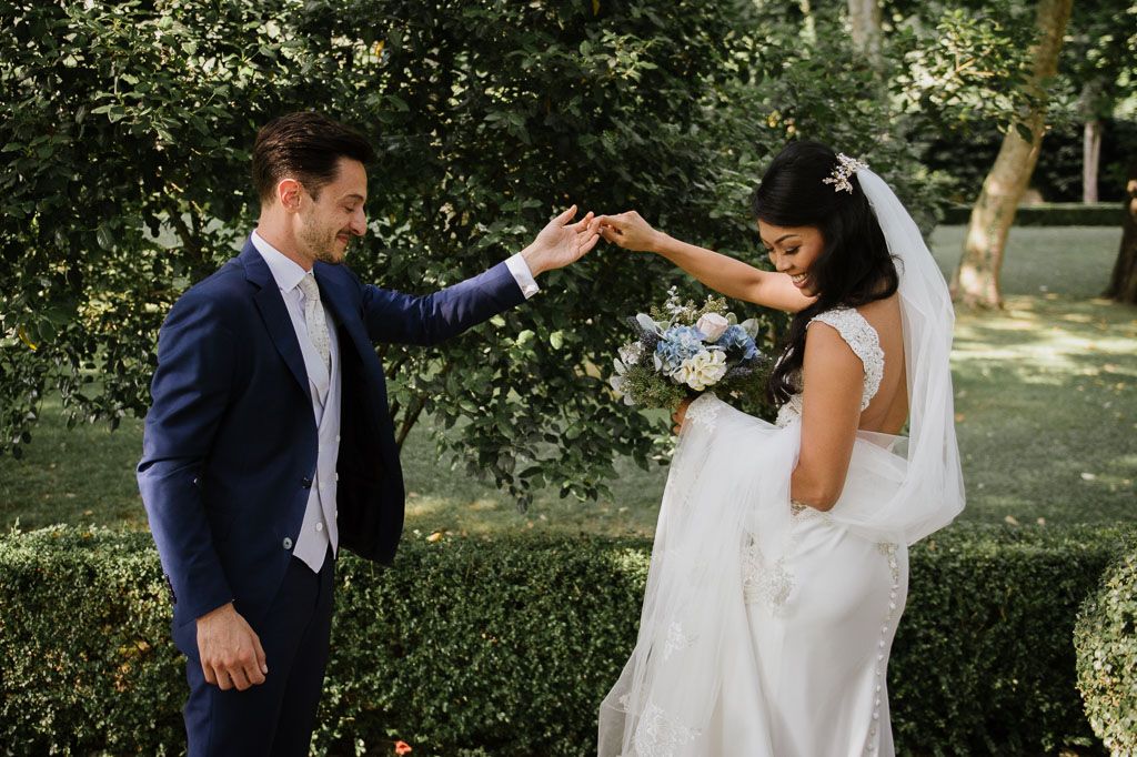 A couple shares a tender moment outdoors surrounded by lush greenery during their wedding day.