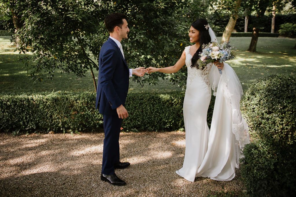 A romantic outdoor wedding photoshoot with couple in navy suit and white dress amongst trees and natural light.