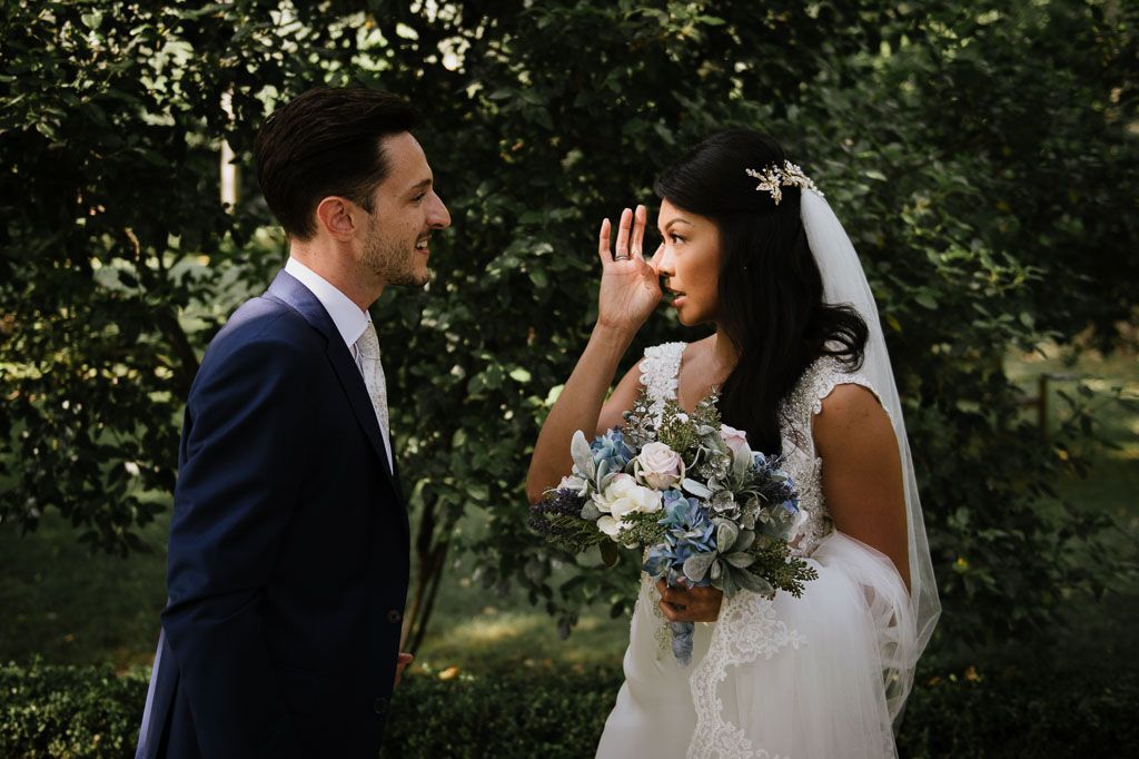 Elegant wedding couple shares intimate moment in outdoor garden setting with soft natural lighting.