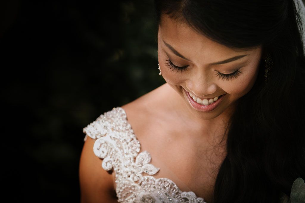 Bride wearing delicate lace dress details captured in soft natural light.