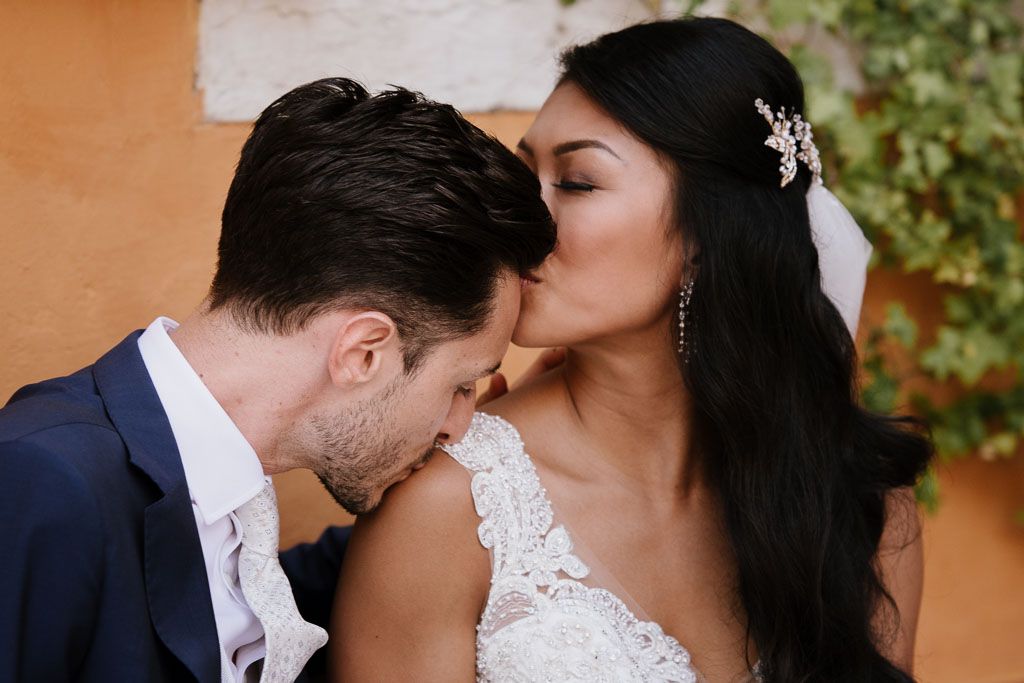 A romantic wedding moment as a couple shares a tender kiss during their ceremony outdoors.