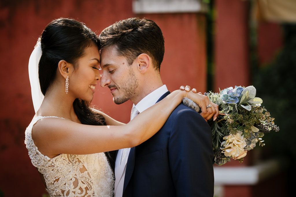 A romantic wedding moment between newlyweds standing close together against a warm background.