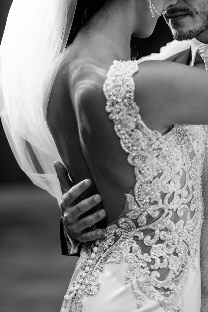 Detailed black and white close-up of an intricate lace wedding dress back with delicate beading patterns.