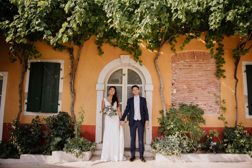 Yellow villa exterior with climbing vines and arched windows creates a romantic Italian wedding backdrop.