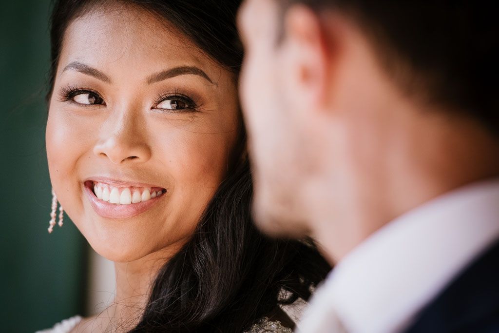 Close up portrait showcasing elegant bridal makeup and jewelry against dark background.