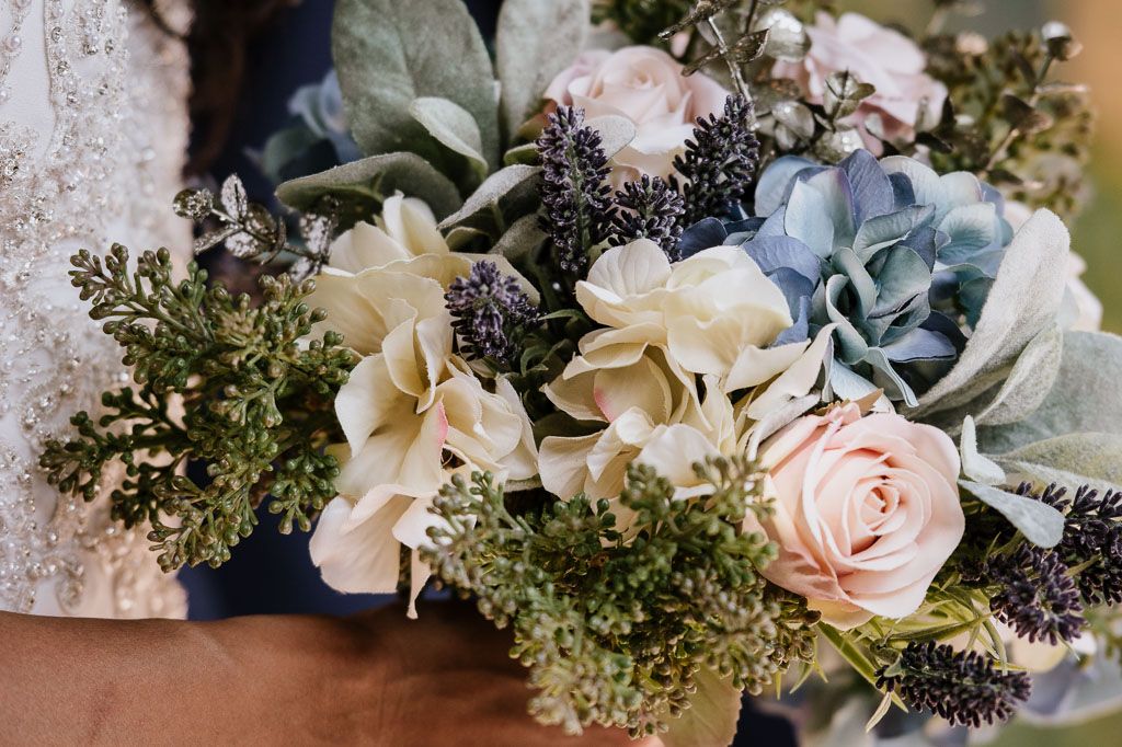 Elegant wedding floral arrangement with soft pink roses and blue flowers against a light background.