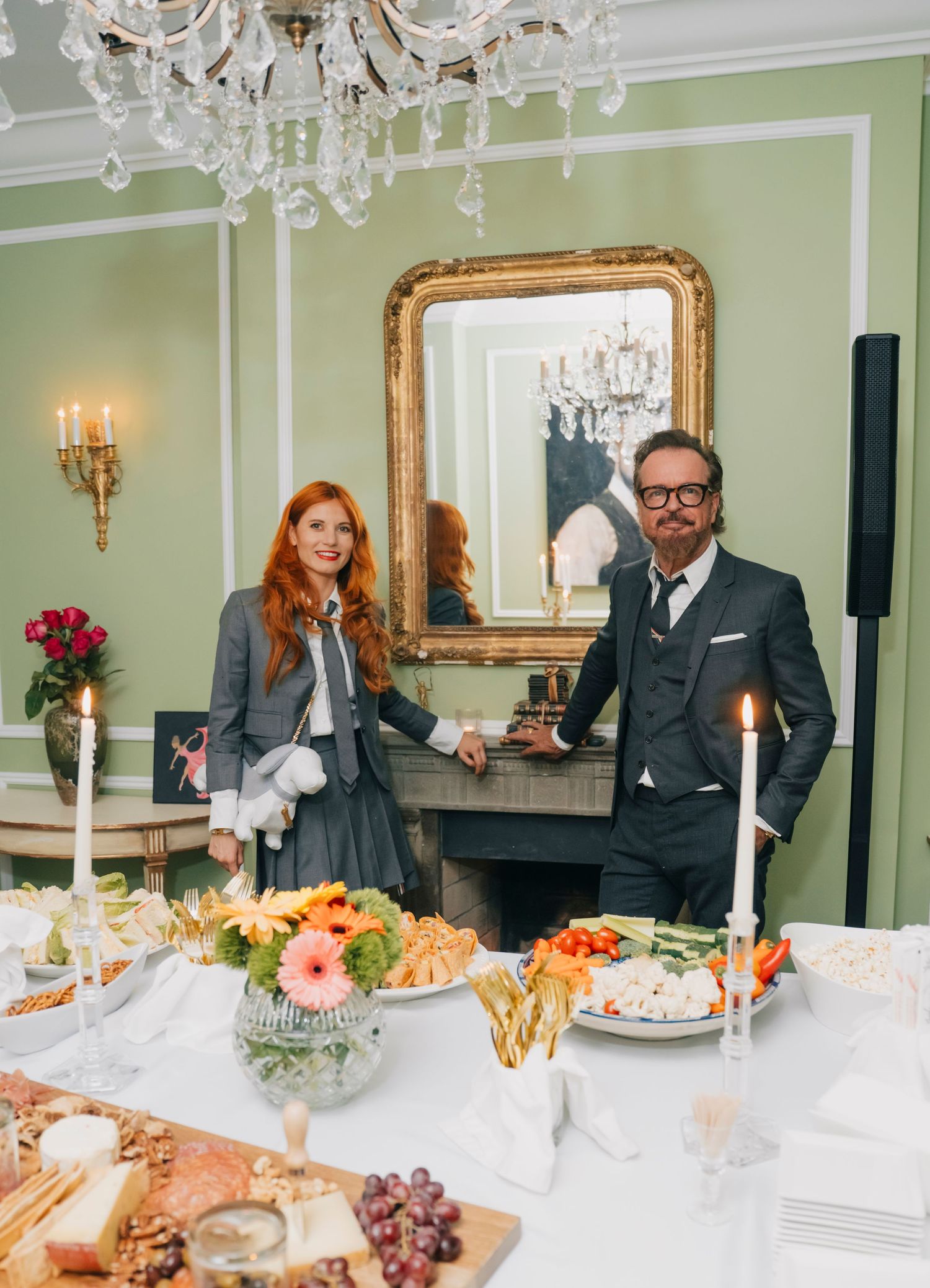 Elegant banquet table with crystal chandeliers overhead and ornate decor in a mint green dining room with gilded details.