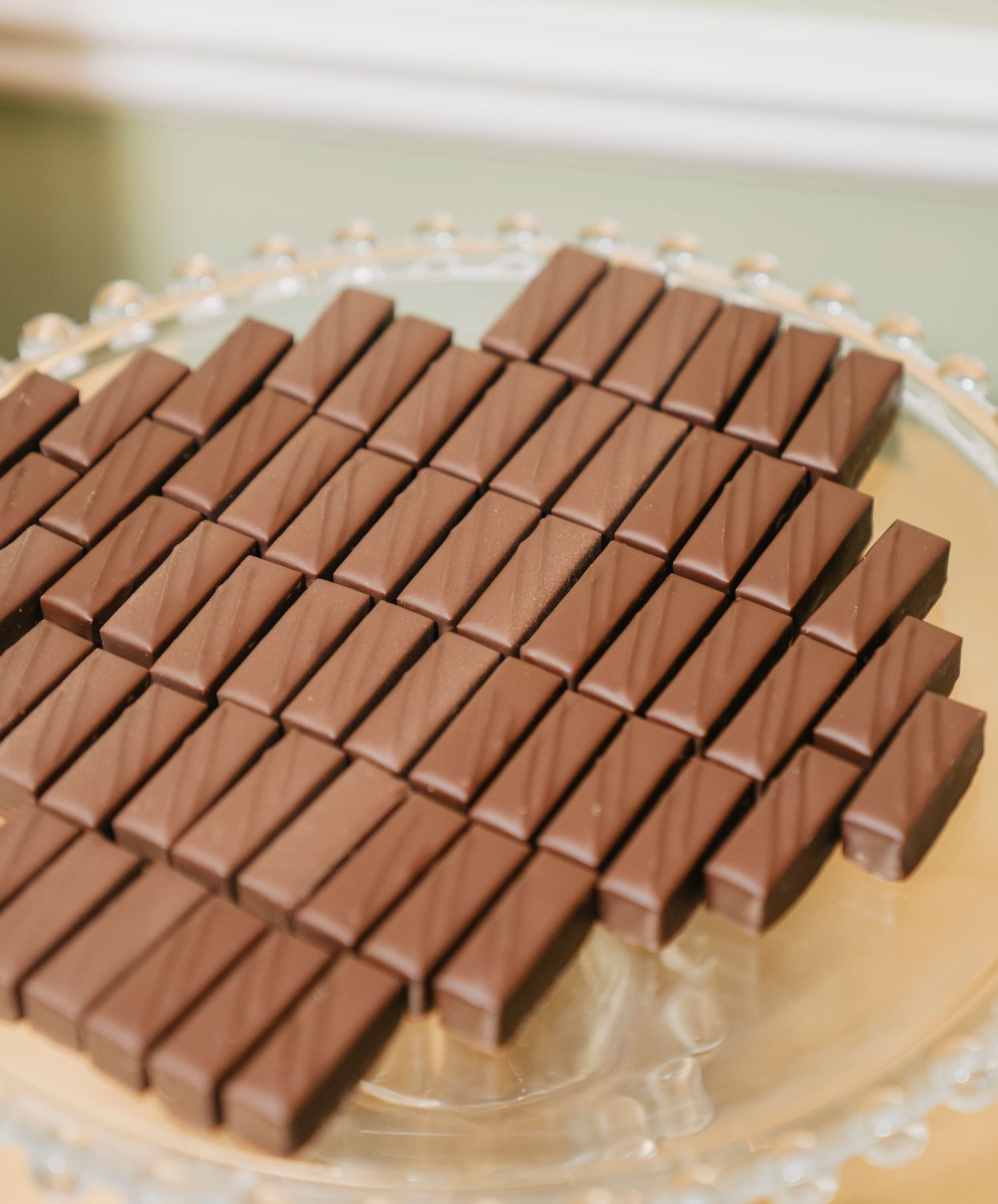 Several rows of small chocolate bar segments displayed in a diagonal pattern on a light colored surface.