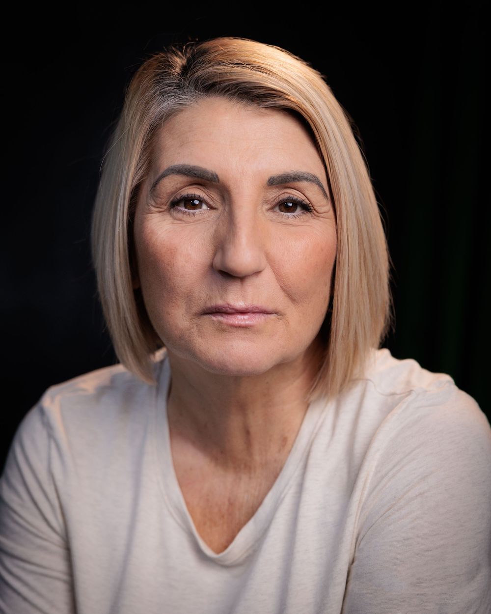 A woman with blonde hair in a white sweater shown in multiple profile angles against a dark background.