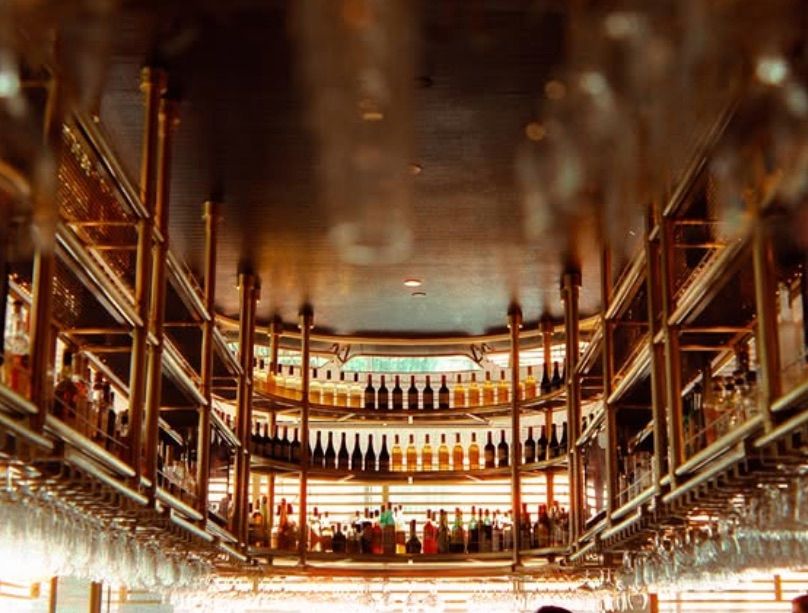 A panoramic view of a luxurious bar with rows of wine glasses hanging from fairmont hotel in pittsburgh pa wedding film photography.