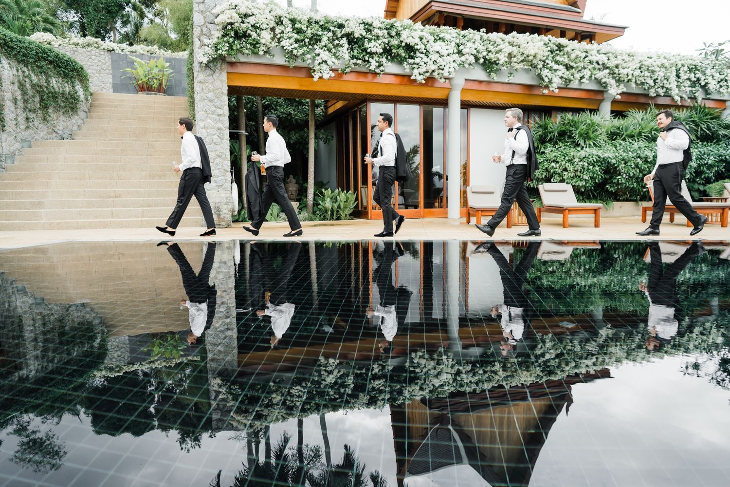 People in business attire walk through a modern office hallway with reflective floors and natural lighting.