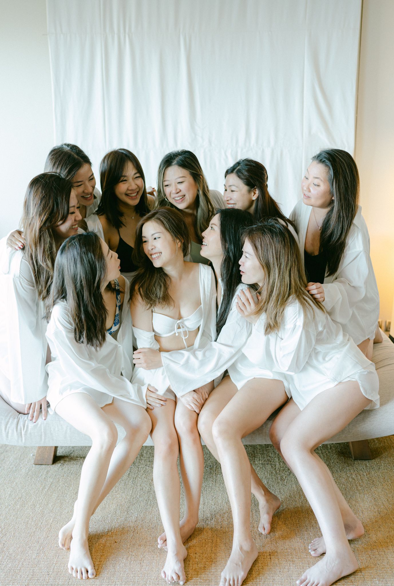 Group of women in white robes posing playfully for a pre-wedding photoshoot.