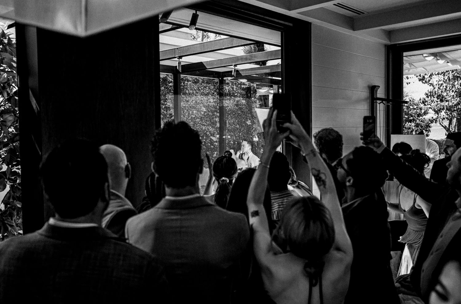 Wedding guests raise their hands in celebration during an indoor ceremony.