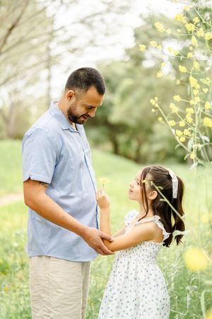 A joyful outdoor family photoshoot in a sunlit field with yellow wildflowers.
