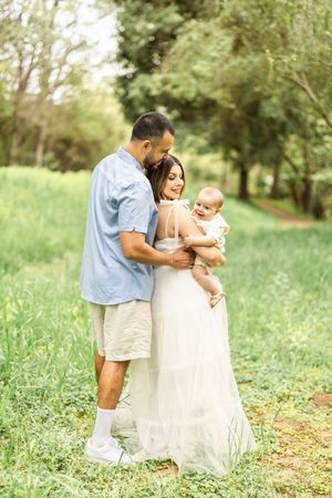 A tender family moment captured in a grassy meadow during golden hour.