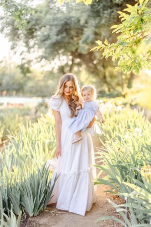 White-dressed figures walking among tall iris plants in a sunlit garden.