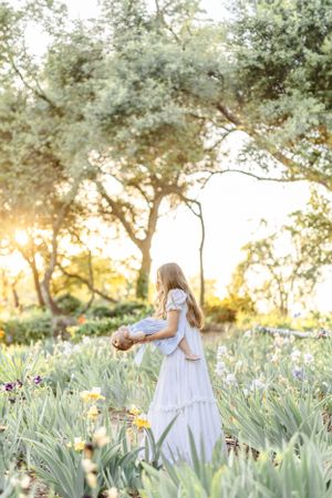 White-dressed figure walking through garden of iris flowers at golden hour.