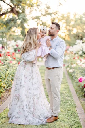 Family shares joyful moment together among blooming rose garden at sunset.