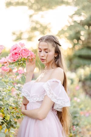 A dreamy photoshoot in a rose garden at sunset with soft bokeh lighting and pink blooms.