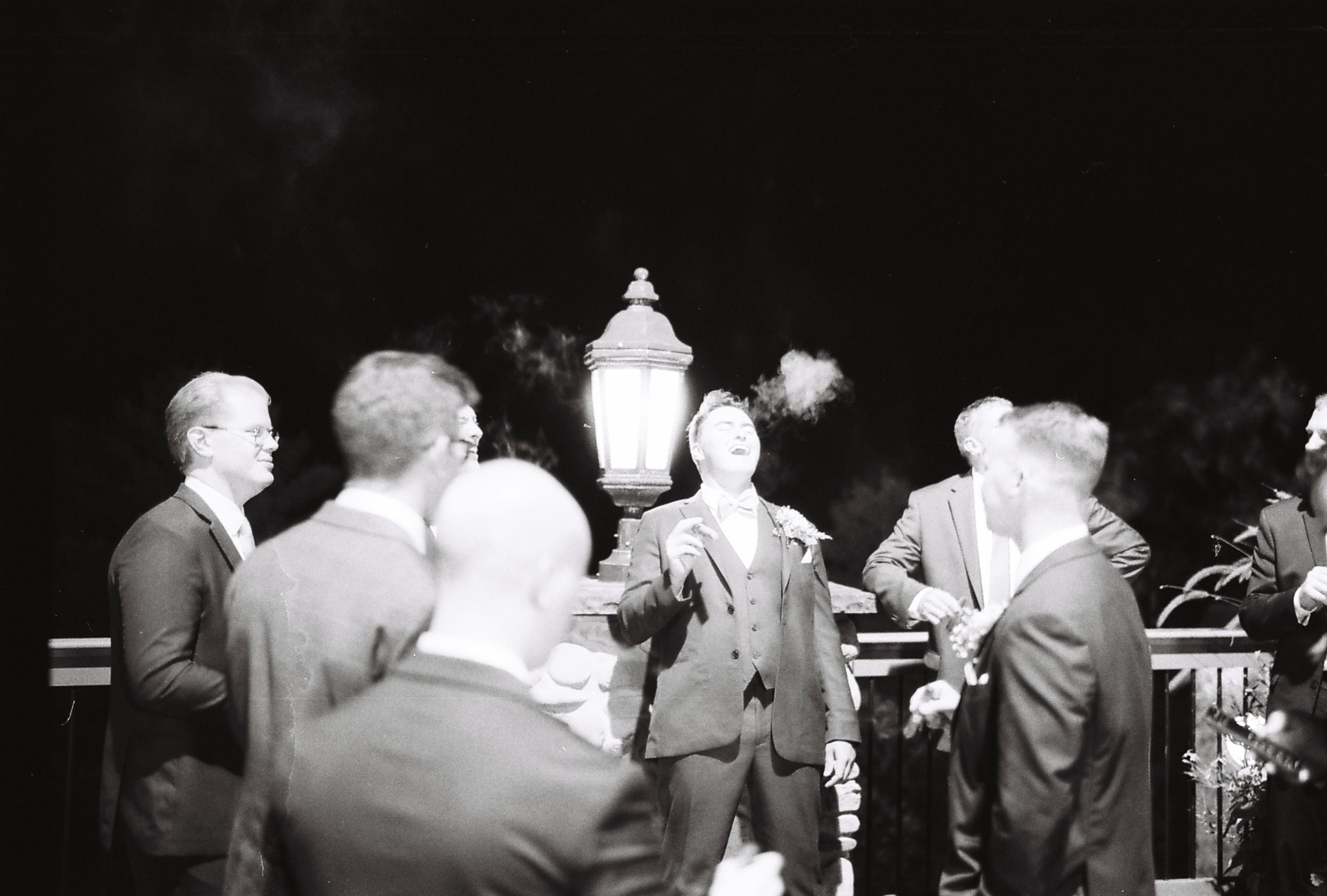 Monochrome photograph showing silhouettes of people gathered at a formal event.