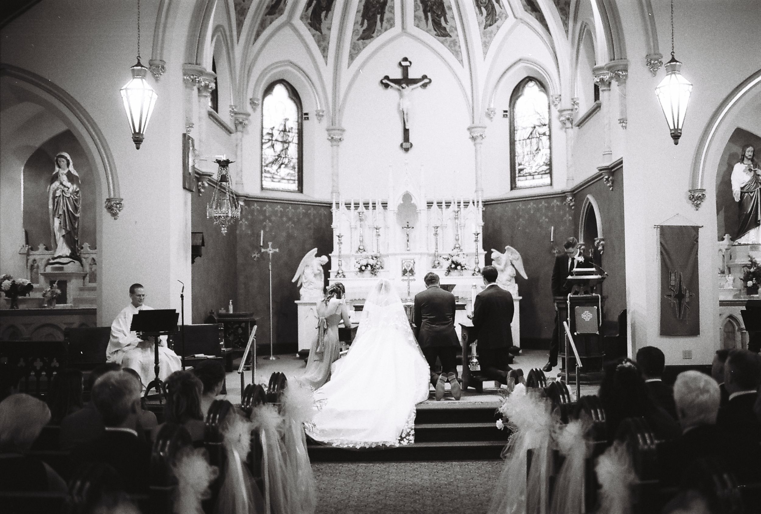 A traditional Catholic church wedding ceremony taking place in a Gothic-style sanctuary with vaulted ceilings and stained glass.