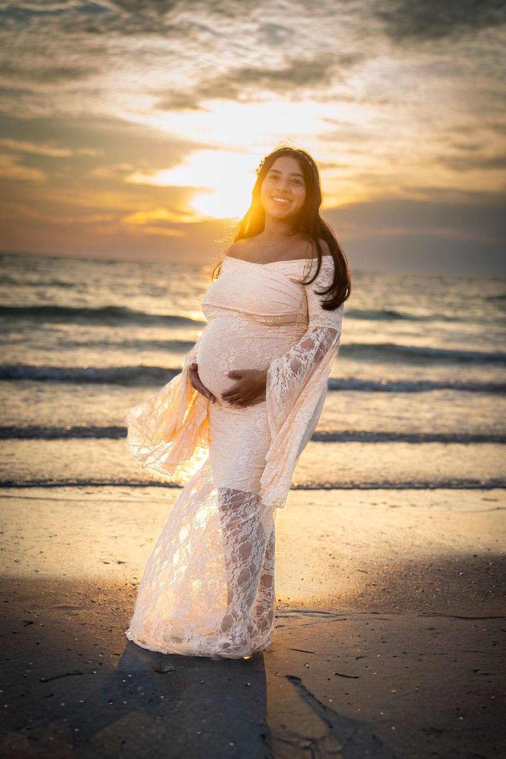 White lace dress flows gracefully during a romantic beach photoshoot at golden hour sunset by the ocean waves.